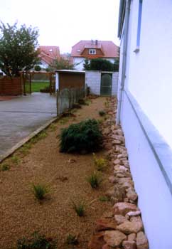 Das Baurecht erzwingt gewisse Abstände beim Hausbau.<br>Doch was tun mit diesem 2,2 m breiten Streifen, der optisch mehr zum Nachbarn gehört? Gewünscht war eine günstige und pflegeleichte, optisch ansprechende Gestaltung. Unsere Lösung: Einfach gestaltete Steinanlage mit strukturierender Pflanzung. Gartenbau, Landschaftsbau, Hausgarten, Trockenmauern, Sichtschutz, Steingarten, Pflanzungen, Garten-Umgestaltungen, Garten-Neuanlagen, Sitzmauern, Polygonalbeläge, Teich, Terrassen, mediterraner Garten, Baumfällungen, Gartenpflege